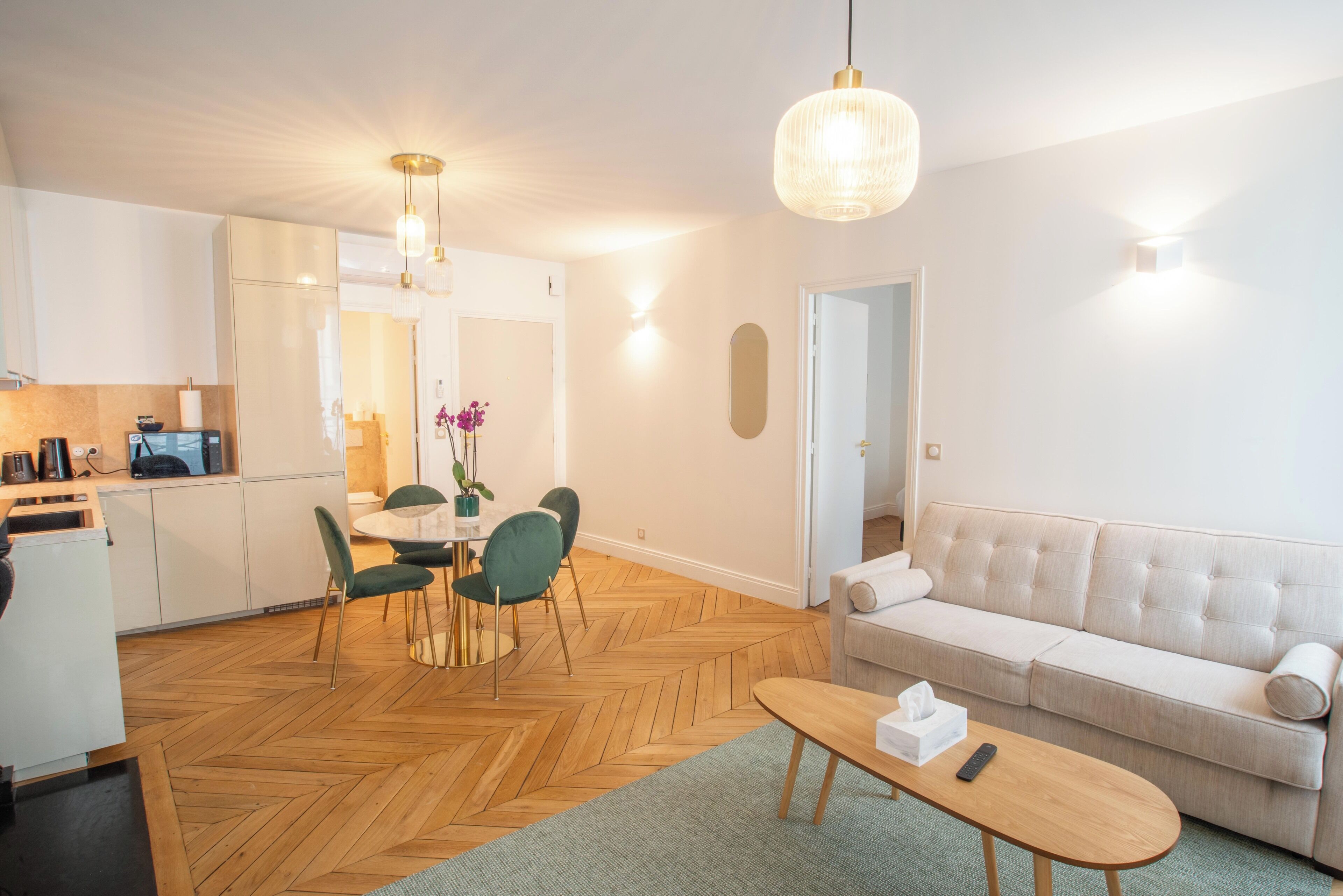 A modern living room with a sofa, a coffee table, and a dining area with chairs and a table.