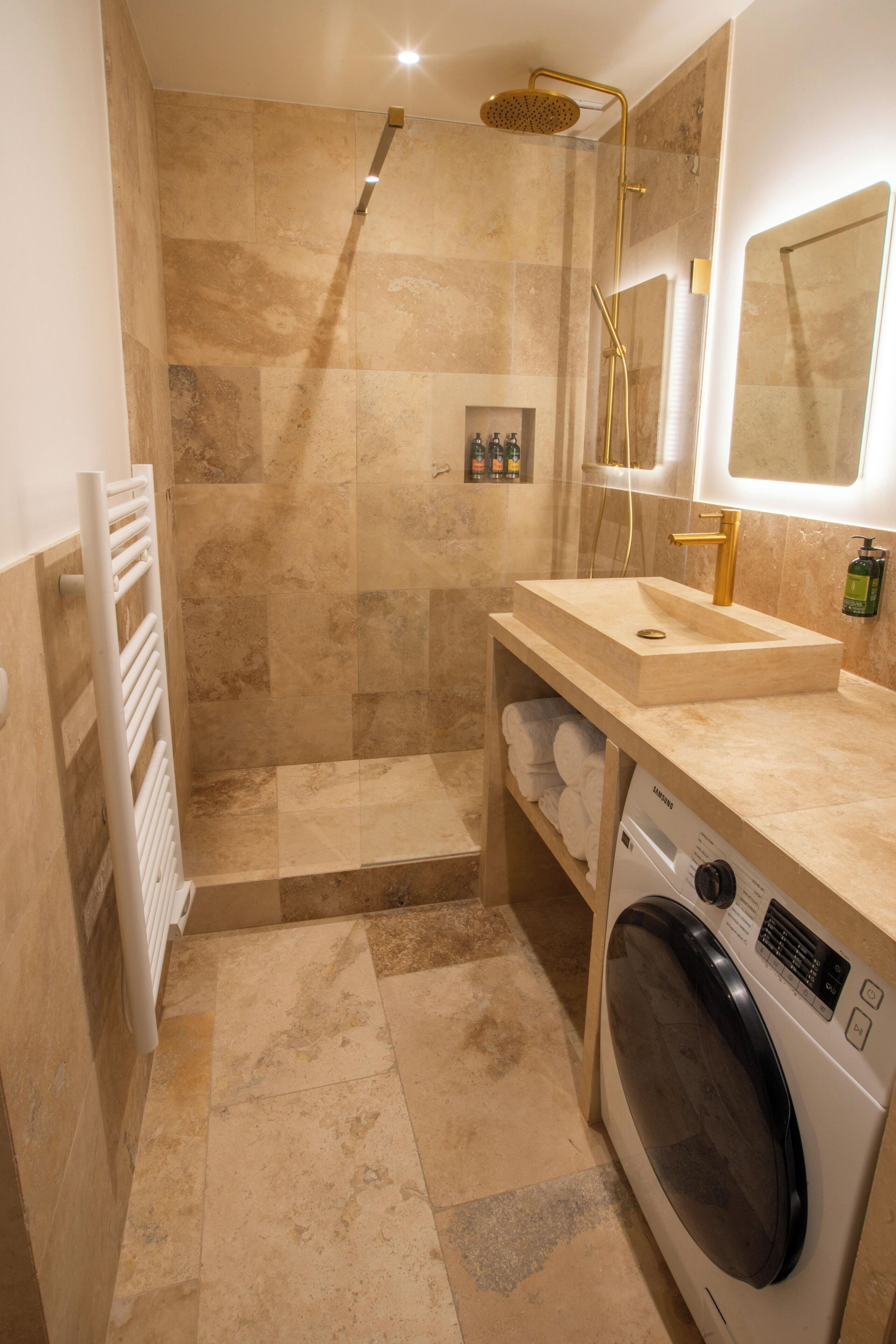 A modern bathroom with a walk-in shower, a built-in sink, a toilet, and a washing machine.