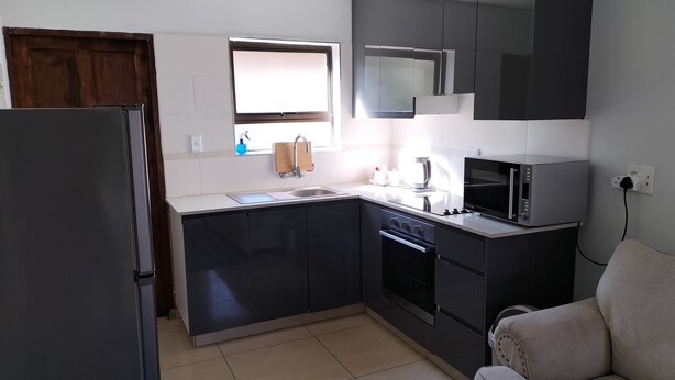 Una cocina moderna con armarios oscuros, un refrigerador de acero inoxidable, un microondas y un horno.