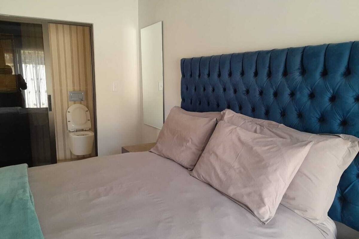 A bed with a tufted headboard, two pillows, and a light-colored bedspread.