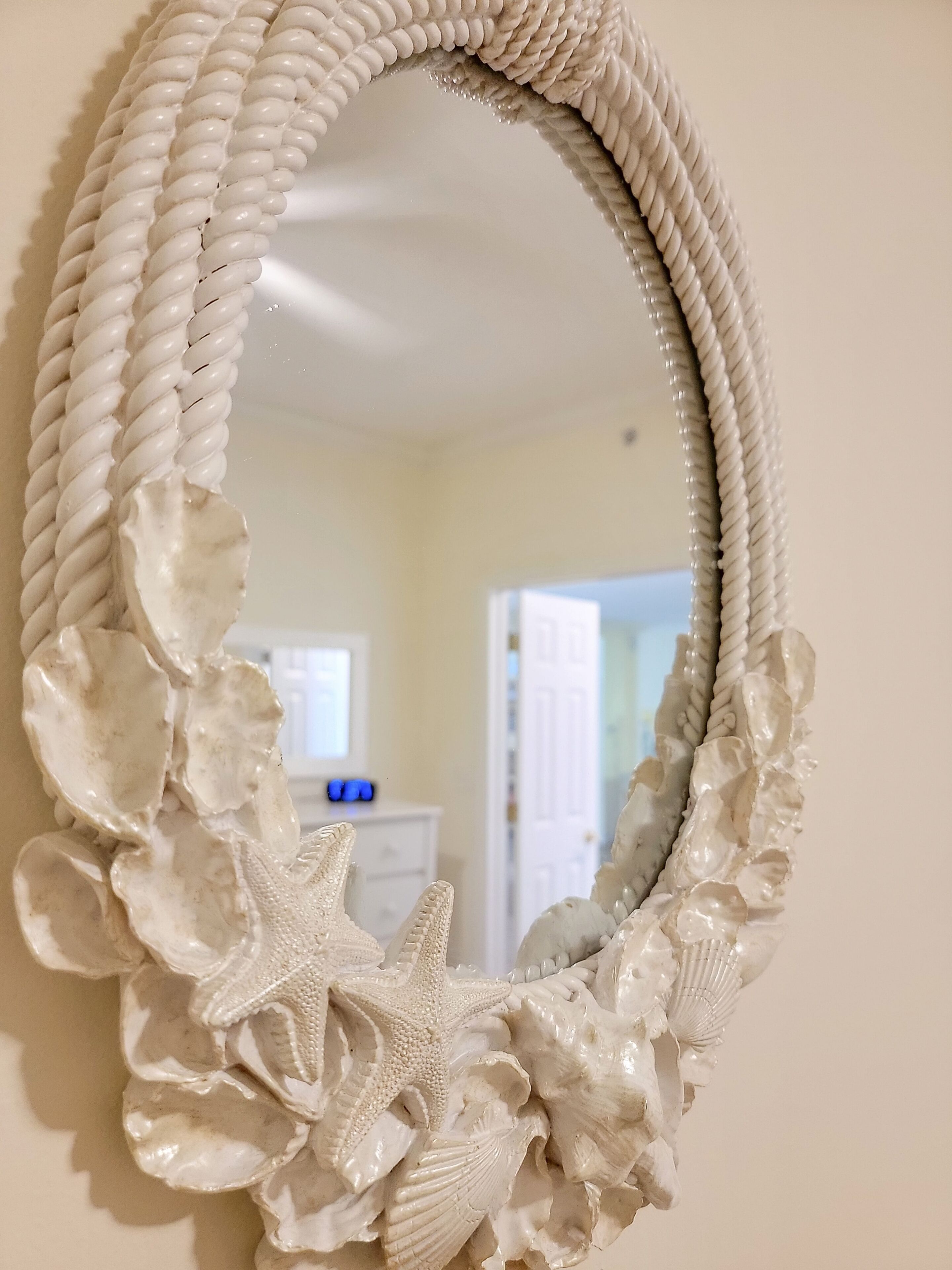 A white, ornate mirror with a rope-like frame and sea-themed decorations including a starfish and seashells.
