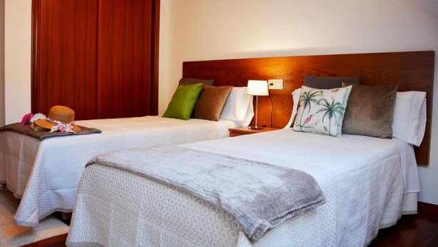 Habitación de hotel con dos camas, cabeceros de madera y un ventanal grande.