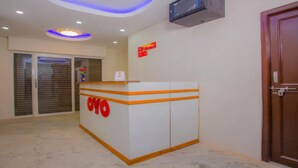Een receptiebalie met een bordje met de tekst 'OYO' in een hotel lobby, met een gesloten deur en een raam met jaloezieën.