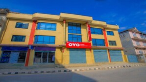 Een hotel met een gele gevel, meerdere ramen en een rood bord waarop staat dat het het OYO Hotel Vipassana Inn is.