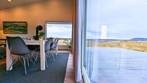 A modern dining area with a view of the beach. - Austurey Lakefront Villa (Bláskógabyggd)