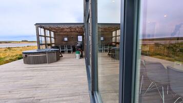 Une terrasse en bois avec un jacuzzi, un espace salon extérieur et un coin barbecue.