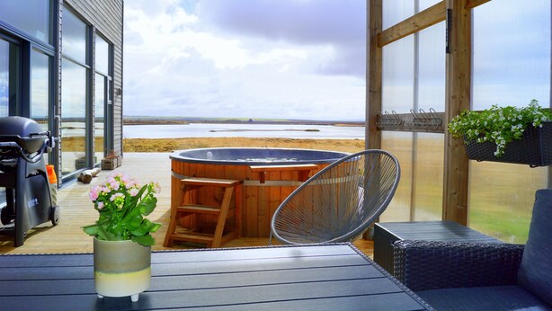 Un espacio al aire libre techado con un jacuzzi, asientos y vistas a la playa.