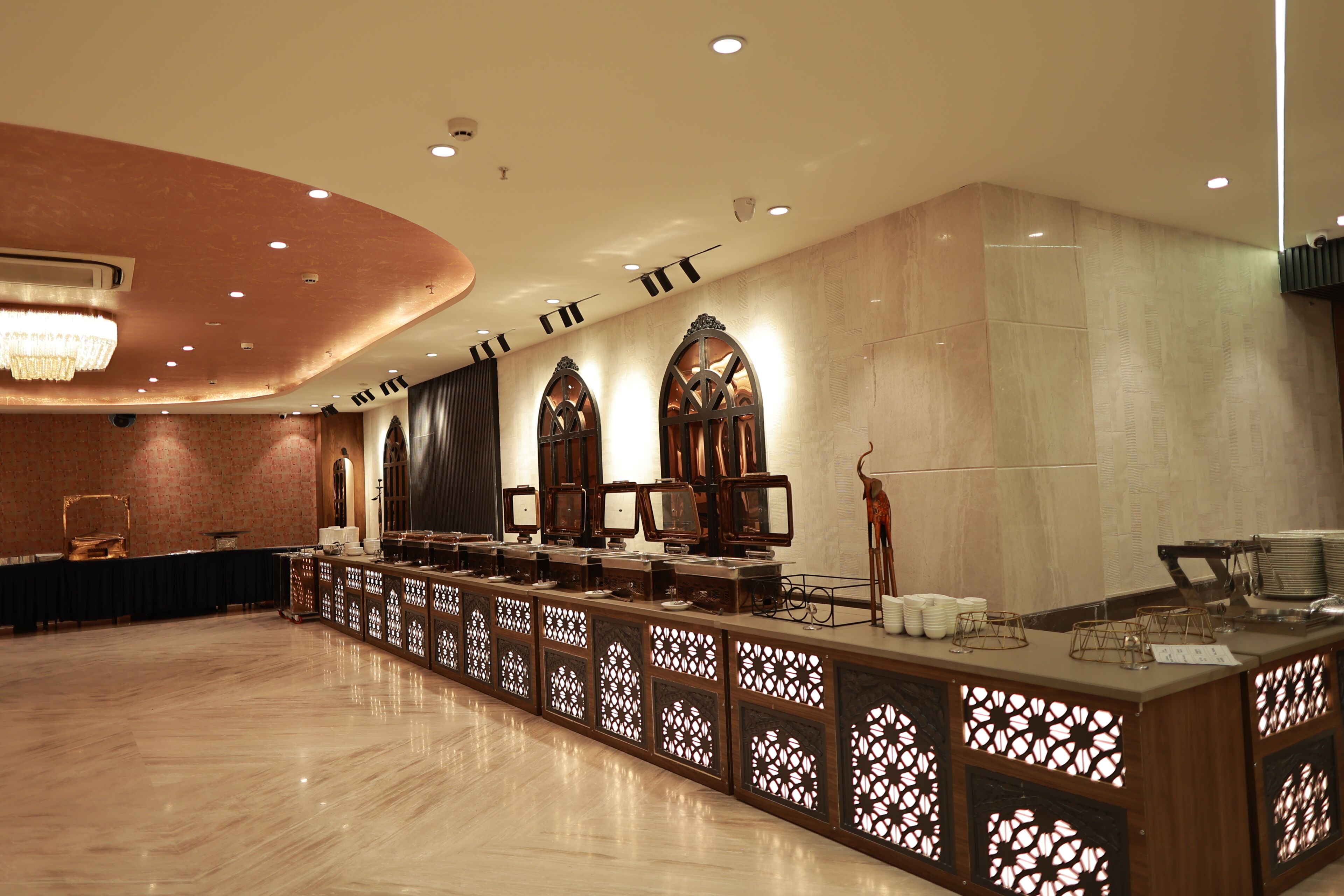 A hotel lobby with a reception desk, decorative screens, and a chandelier.