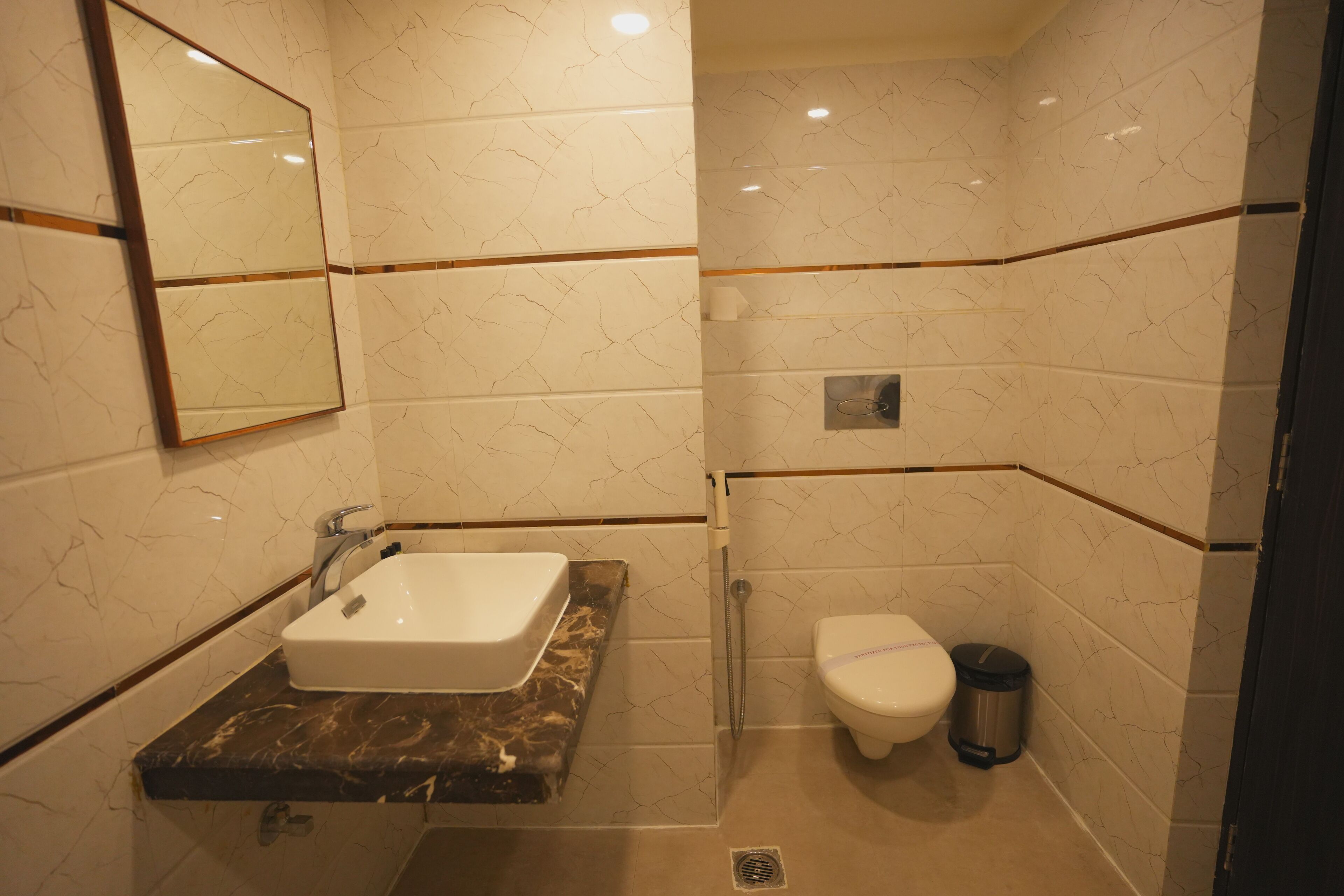 A bathroom with a marble sink, a toilet, and a trash bin.
