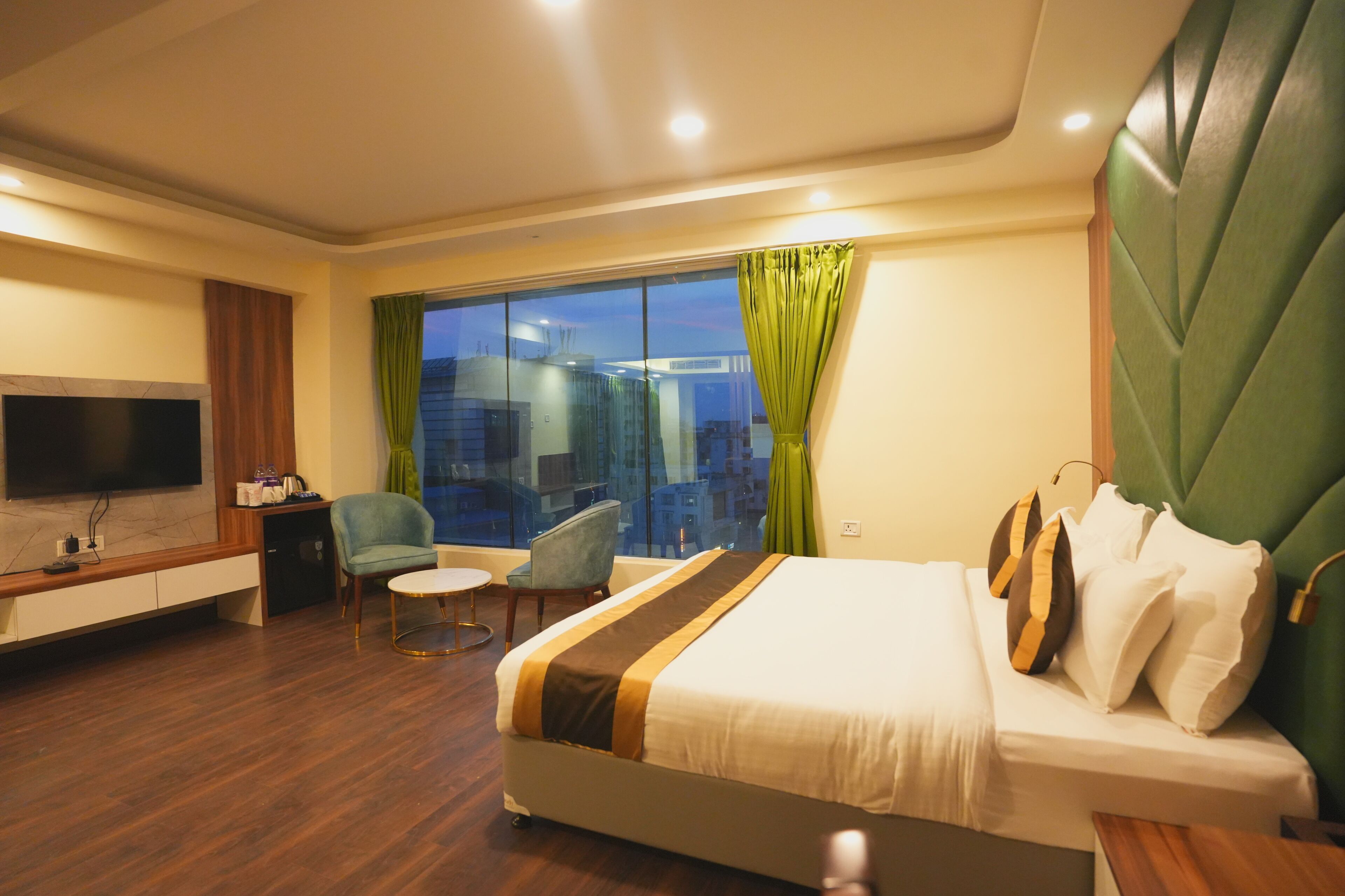 Habitación de hotel con una cama grande, televisión, escritorio y una silla.