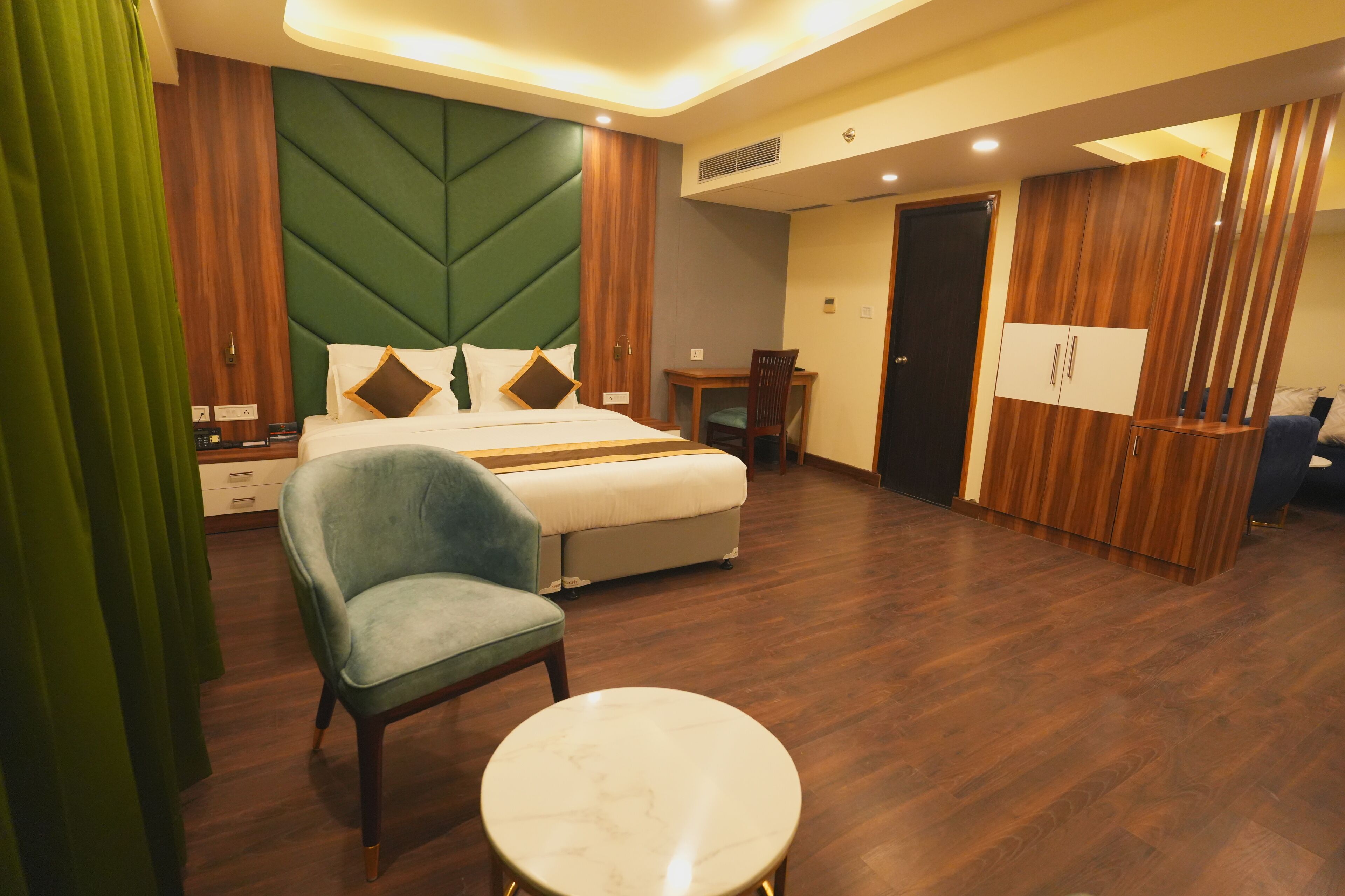 A hotel room with a bed, a desk, a chair, and a small table.