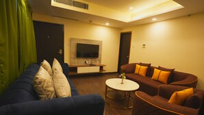 A living room with a blue sofa, a brown sofa, and a round coffee table. - Hotel CP Palace (Patna)