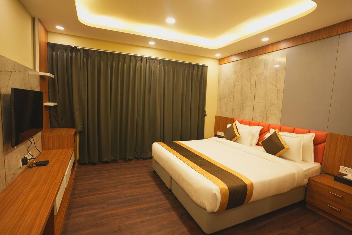 Una habitación de hotel moderna con una cama grande, mesitas de noche de madera, un televisor de pantalla plana y una pared decorativa de mármol.