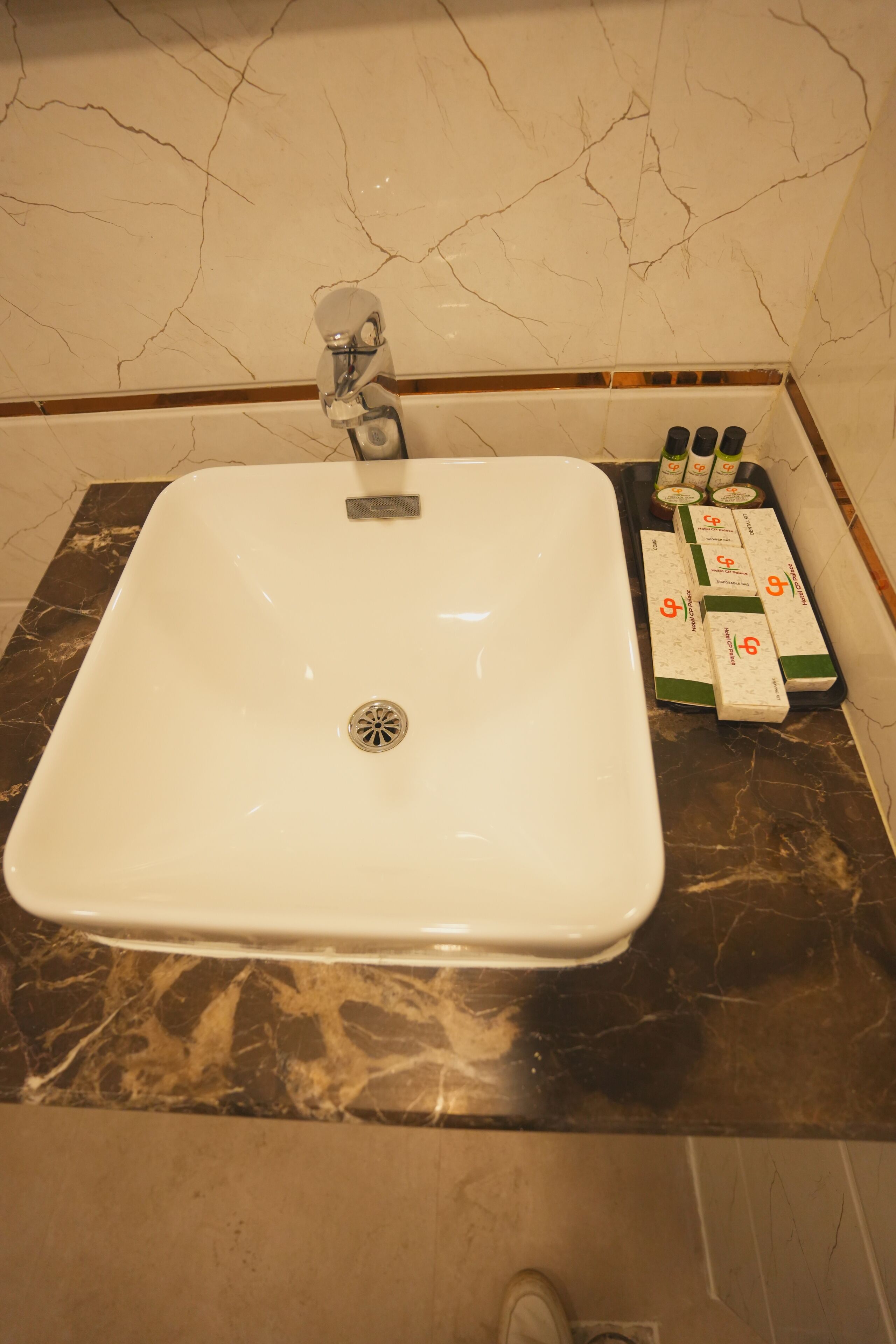 Une salle de bain avec un lavabo blanc, un comptoir en marbre et un flacon de savon pour les mains.