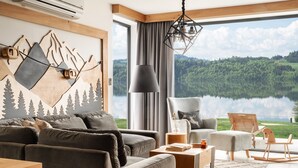 A modern living room with a large window, a mountain-themed wall art, a sofa, a chair, and a table with a book and a vase. - Czorsztyn Prestige (Czorsztyn)
