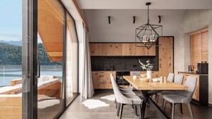 A modern kitchen with wooden cabinets, a black countertop, and a dining area with a wooden table and grey chairs. - Czorsztyn Prestige (Czorsztyn)