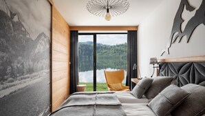 A bedroom with a large bed, a view of a lake, and a mountain painting on the wall. - Czorsztyn Prestige (Czorsztyn)