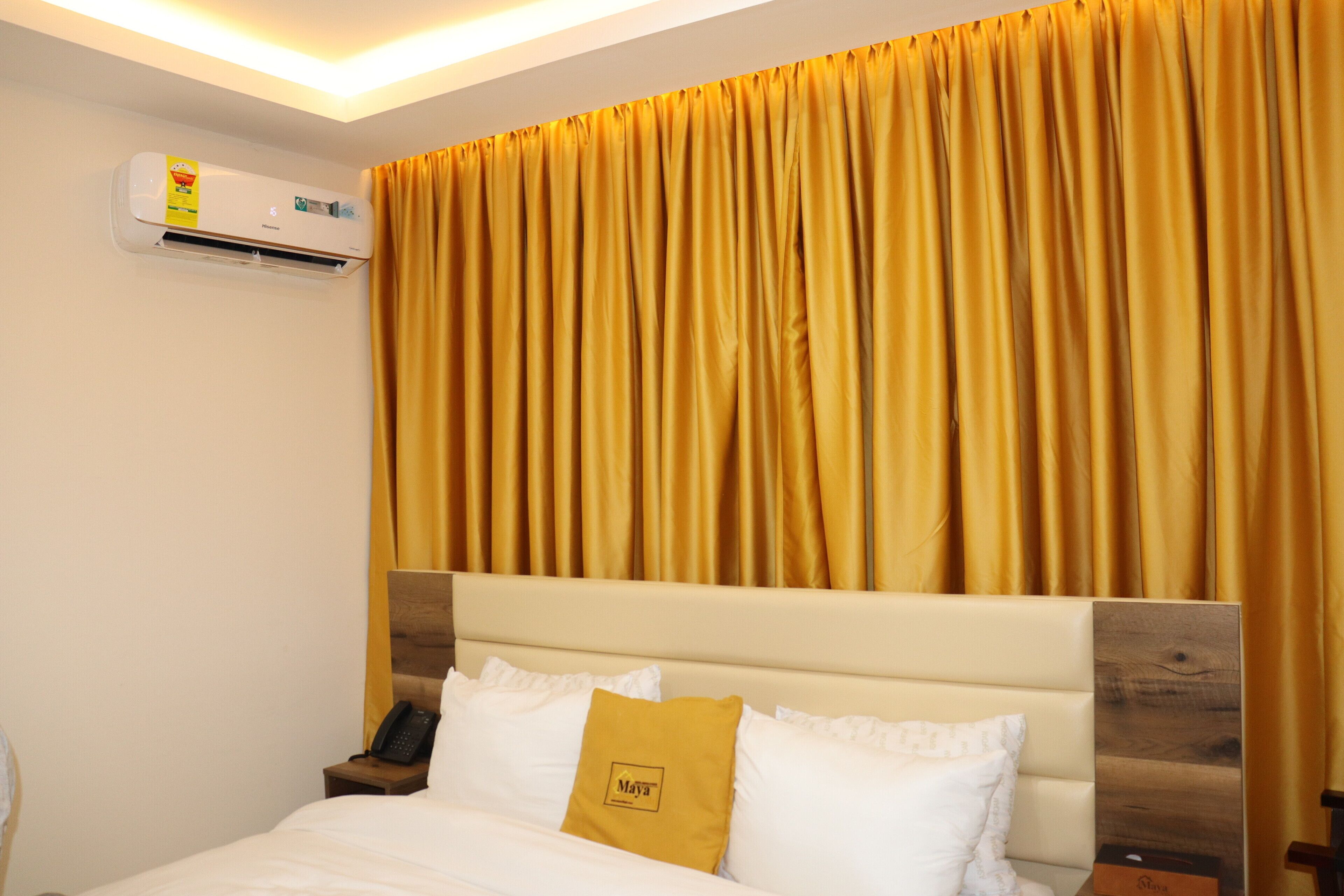 Ein Hotelzimmer mit Bett, Kopfteil, Wandklimaanlage und Vorhang.