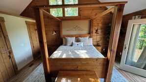 Een slaapkamer met houten vloer, een bed, nachtkastjes en een raam.