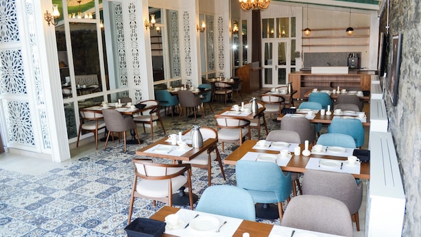 Un restaurante con varias mesas y sillas, un suelo estampado y paneles decorativos en la pared.