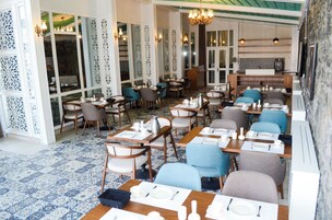 Un restaurante con varias mesas y sillas, un suelo estampado y paneles decorativos en la pared.