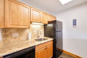 Kitchen features a modern design with a clean, functional layout, including a dishwasher, refrigerator, and tiled backsplash.
