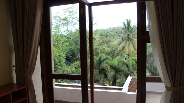 A room with a large window overlooking a lush garden with palm trees. - Kandy Lotus Villa (Kandy)