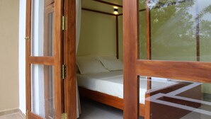 A wooden bed with a mattress and pillows, a wooden frame, and a glass door. - Kandy Lotus Villa (Kandy)