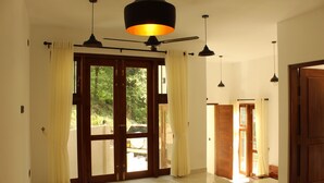 A spacious room with a large sliding glass door leading to an outdoor area, a ceiling fan, and pendant lighting. - Kandy Lotus Villa (Kandy)