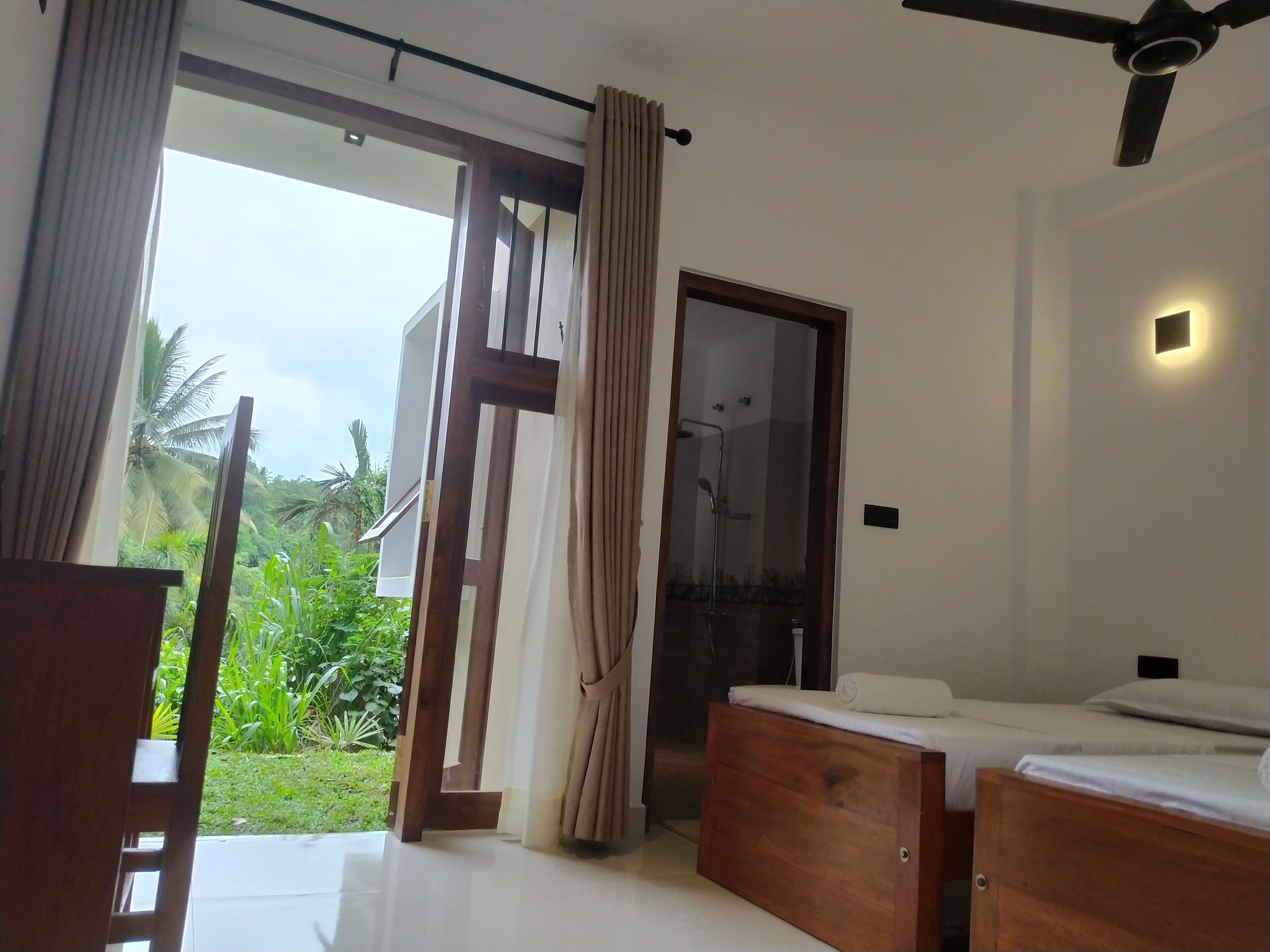 A bedroom with a bed, a ceiling fan, and a view of greenery outside.
