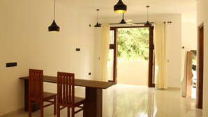 A dining area with a wooden table and chairs, pendant lights, and a ceiling fan. - Kandy Lotus Villa (Kandy)