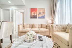 A modern living room with a beige sofa, a marble coffee table with a floral centerpiece, and two remote controls on the table.