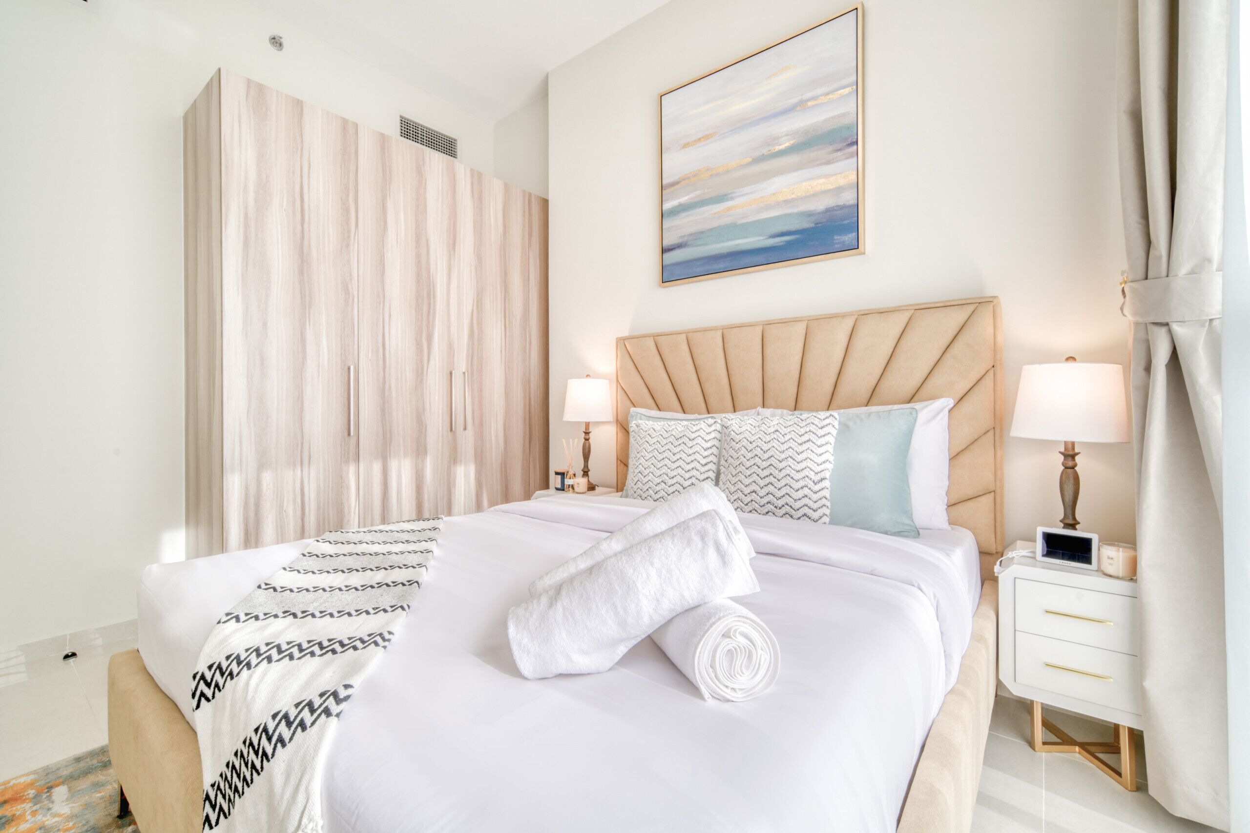 A neatly made bed with a patterned blanket, a wooden headboard, and two bedside lamps.