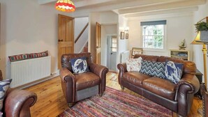 Un salon avec deux canapés en cuir, un tapis coloré et une porte en bois.