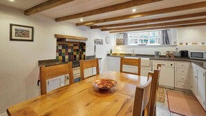 Un coin repas avec une table et des chaises en bois, un mur décoratif aux couleurs vives et une fenêtre agrémentée de rideaux.