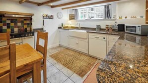 Une cuisine équipée d’une cuisinière, d’un four à micro-ondes et de chaises en bois.