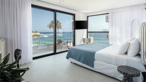 A modern hotel room with a large bed, a TV, and a balcony with a view of the ocean. - Theta Boutique Hotel (Chania)