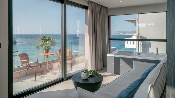 A modern balcony with a view of the sea, a seating area with a table and chairs, and a small kitchenette. - Theta Boutique Hotel (Chania)
