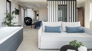 A modern living room with a grey sofa, a black chair, a large mirror, and a potted plant. - Theta Boutique Hotel (Chania)