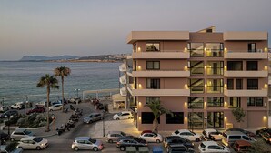 A multi-story hotel with balconies overlooking the sea, a parking lot, and a view of the coastline. - Theta Boutique Hotel (Chania)