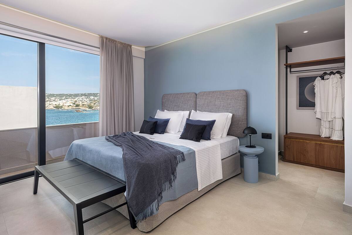 Quarto moderno com uma cama grande, vista para o mar e uma varanda.