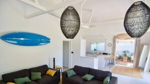 Ein modernes Wohnzimmer mit zwei dunklen Sofas, einem Couchtisch und einem blauen Surfbrett an der Wand.