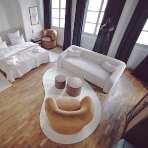 Una habitación de hotel moderna con una cama, un sofá, una mesa de centro redonda y una silla.