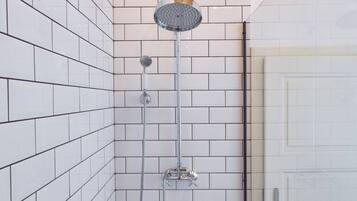 A shower area with white tiled walls and a glass door.