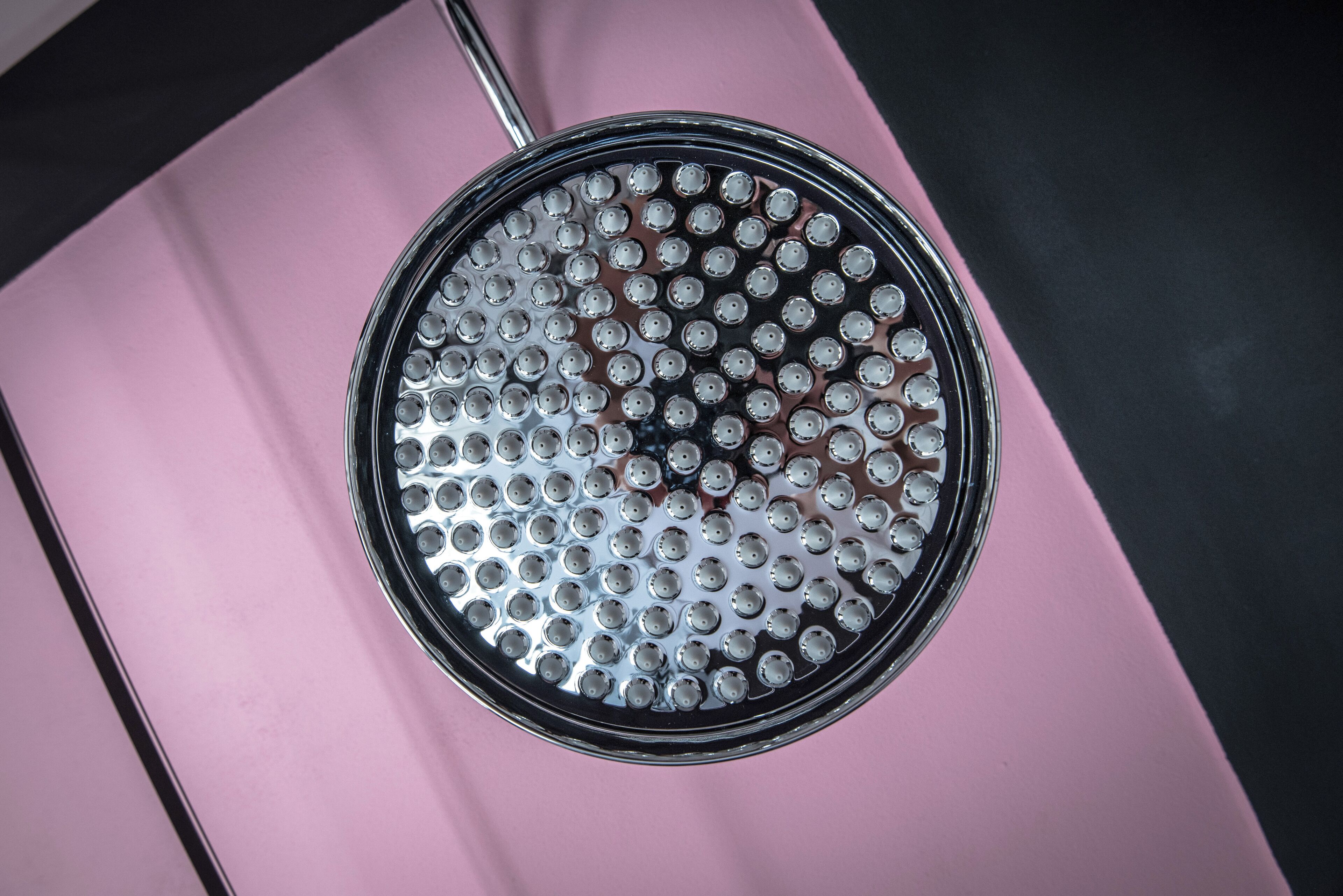 A circular object with multiple holes, likely a part of a machine or equipment, on a pink and black background.