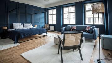 Un dormitorio moderno con una cama con dosel, un sofá, un sillón y ventanas amplias.