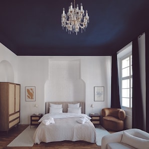 Un dormitorio con una cama grande, una araña, un armario y obras de arte en las paredes.