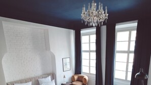 Quarto moderno com cama grande, sofá, lustre e parede de tijolos.
