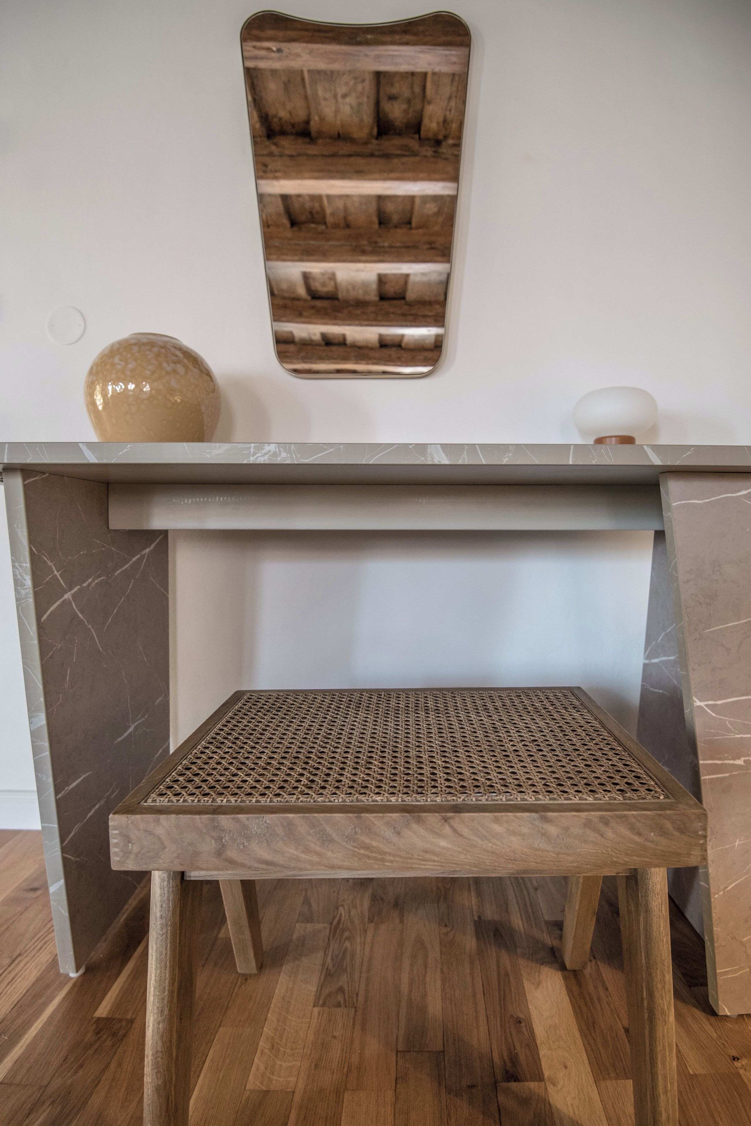 Una mesa de madera con base de mármol y un estante tejido debajo.