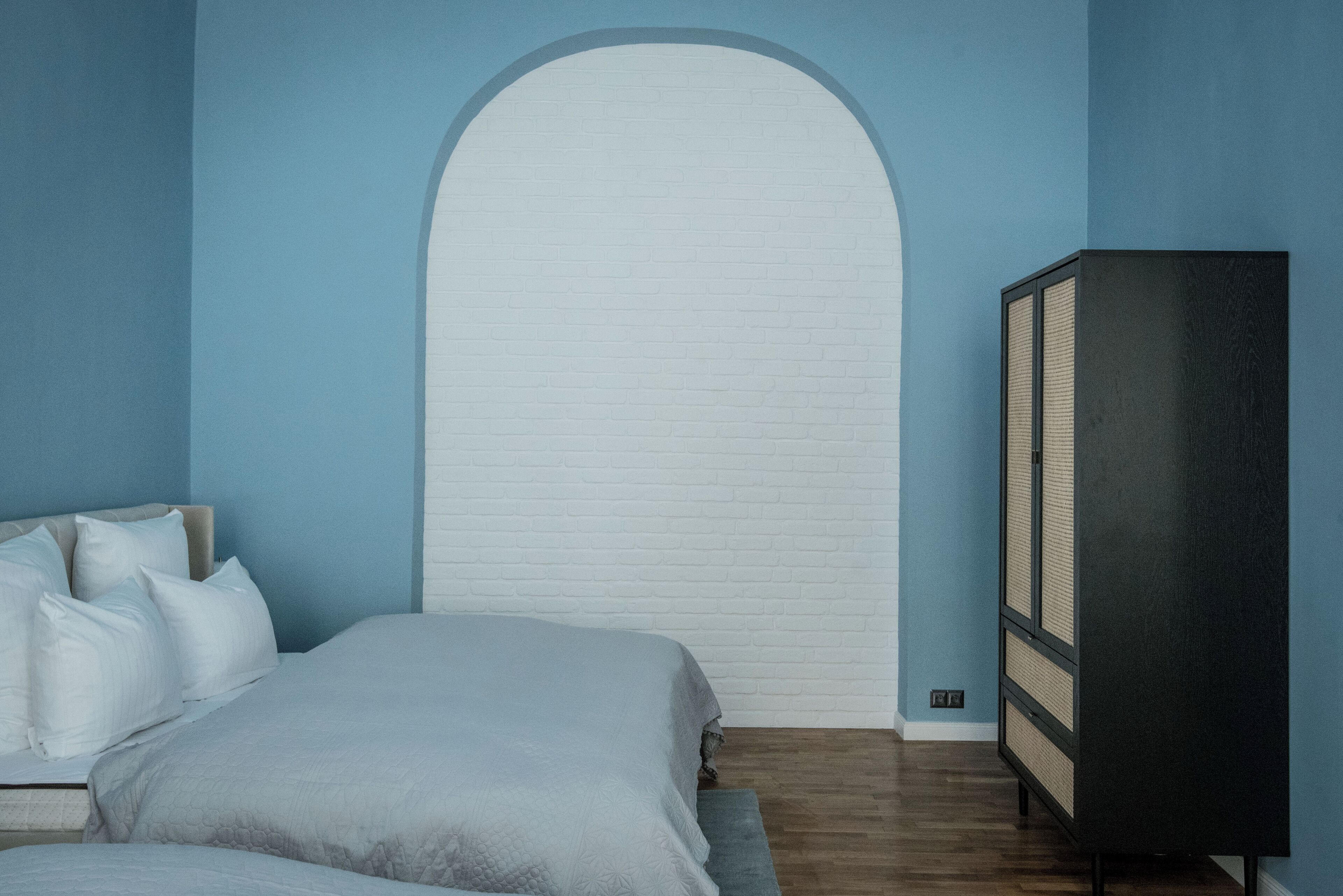 Un dormitorio con cama, armario y pared de ladrillo blanco.